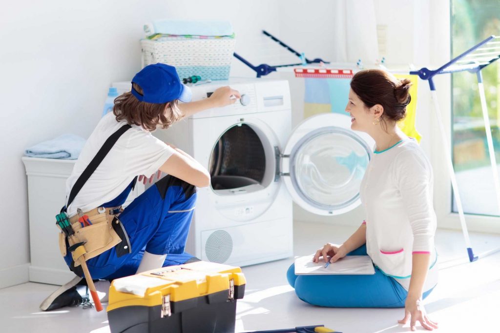 a technician repairing a washer while woman is watching - appliance repair service Gastonia