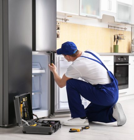 a technician repairing a refrigerator - Gastonia Appliance Repair Pros